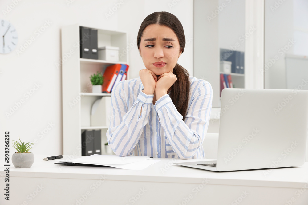 Unhappy young female intern at table in office Unhappy young female intern at table in office