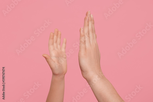 Mother and daughter giving high five on pink background  closeup of hands