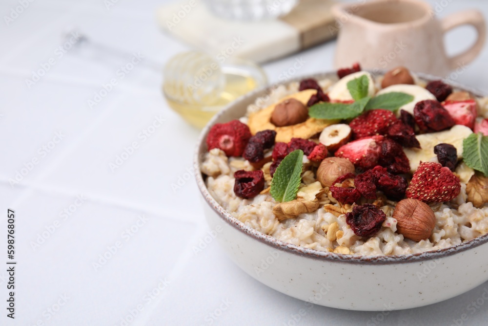Oatmeal with freeze dried fruits, nuts and mint on white wooden table, closeup. Space for text Oatmeal with freeze dried fruits, nuts and mint on white wooden table, closeup. Space for text