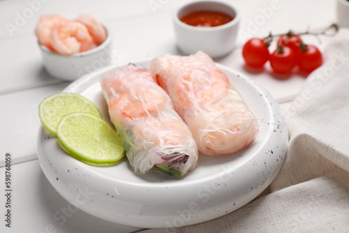 Delicious spring rolls with shrimps wrapped in rice paper on white wooden table, closeup