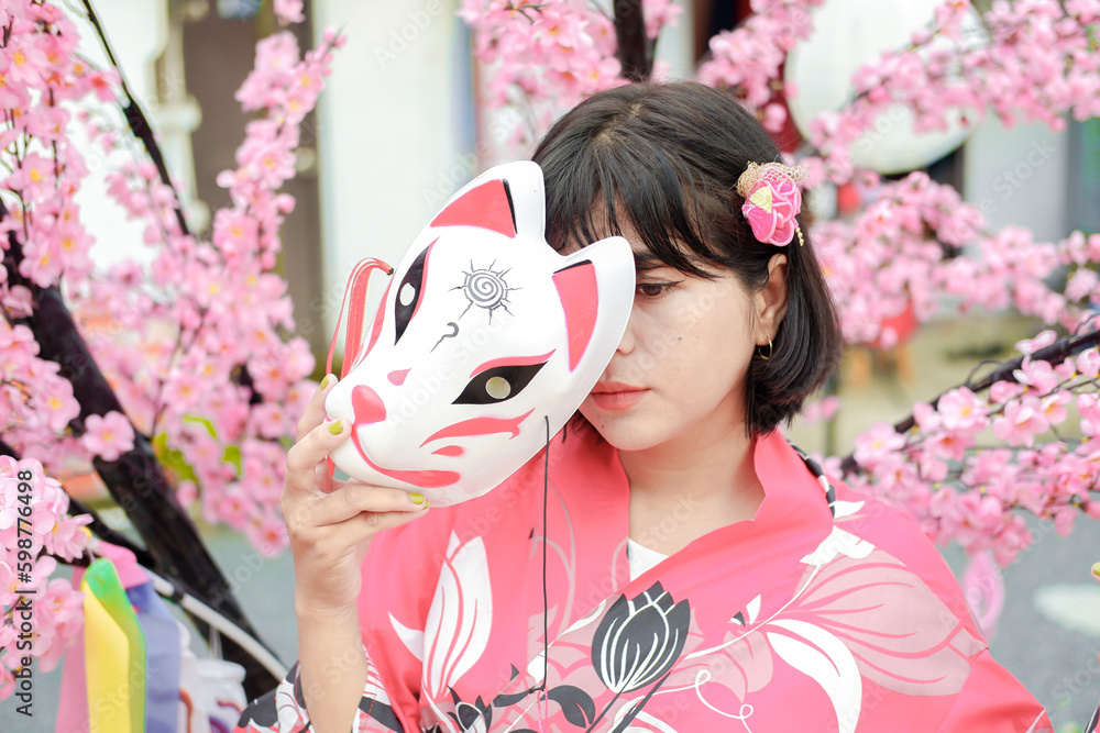 Fototapeta premium Photo of a young woman wearing a kimono against a backdrop of cherry blossoms