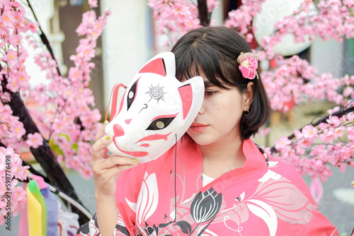 Photo of a young woman wearing a kimono against a backdrop of cherry blossoms