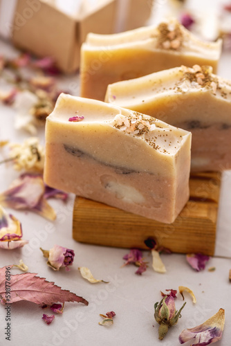 Pieces of delicate fragrant natural handmade soap on a wooden soap dish with dry flower petals around