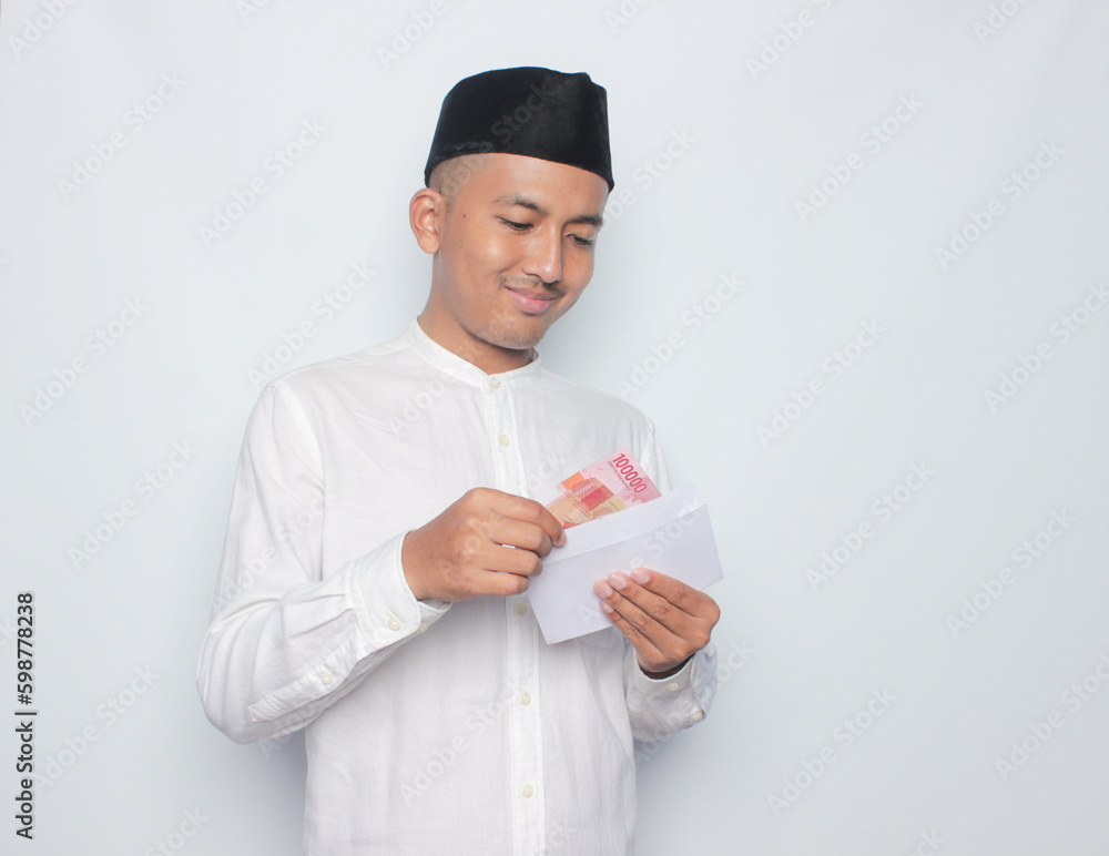 Asian muslim man holding money isolated on white background. Ramadan and eid mubarak concept. Asian muslim man holding money isolated on white background. Ramadan and eid mubarak concept.