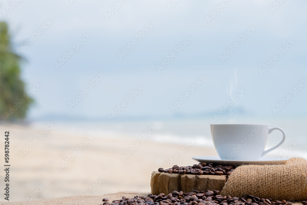 Close-up white coffee cup and many coffee beans placed around on the wood table with a beautiful seascape of nature background, concept coffee vacation travel.