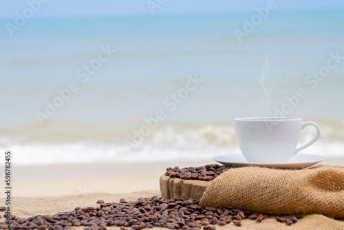 Close-up white coffee cup and many coffee beans placed around on the wood table with a beautiful seascape of nature background, concept coffee vacation travel.