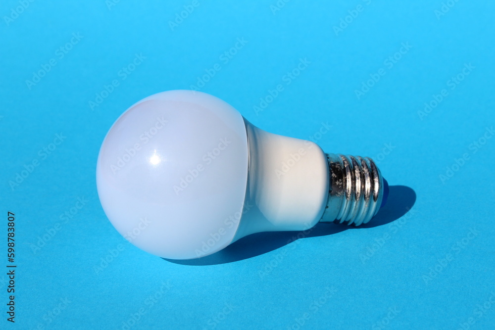 An economical white lamp lies on a blue background. An economical white lamp lies on a blue background.
