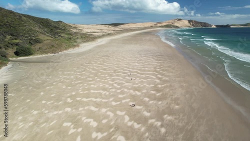 Group of people walking on long sandy Te Werahi Beach, Cape Maria van Diemen. Aerial during summer sunny day. photo