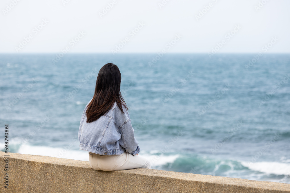 Woman sit beside the waterfront in Taiwan Woman sit beside the waterfront in Taiwan