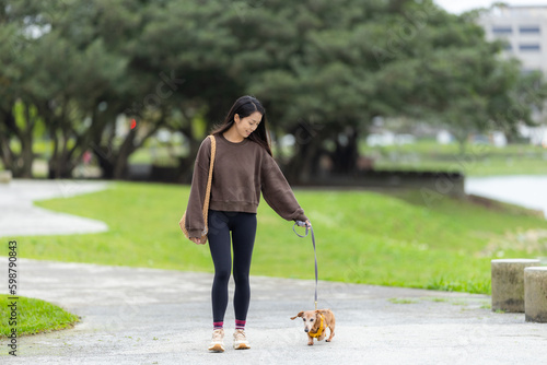 Woman with her dachshund dog walking in the garden