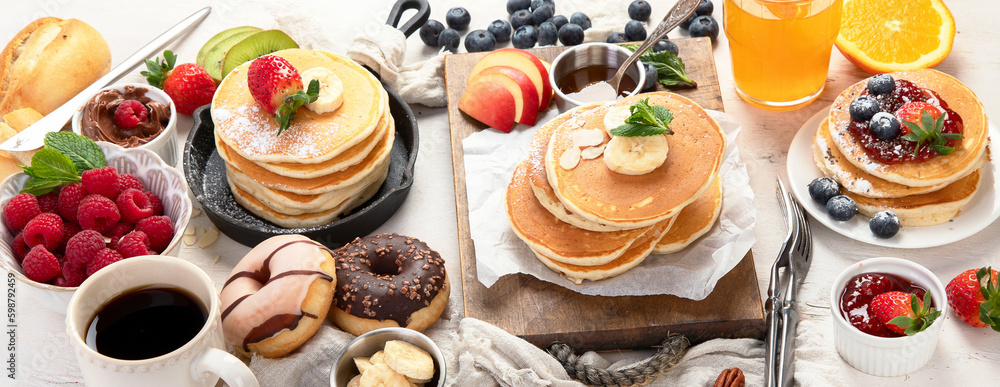 Pancakes with fresh fruits, donuts and coffee on a white background. Pancakes with fresh fruits, donuts and coffee on a white background.
