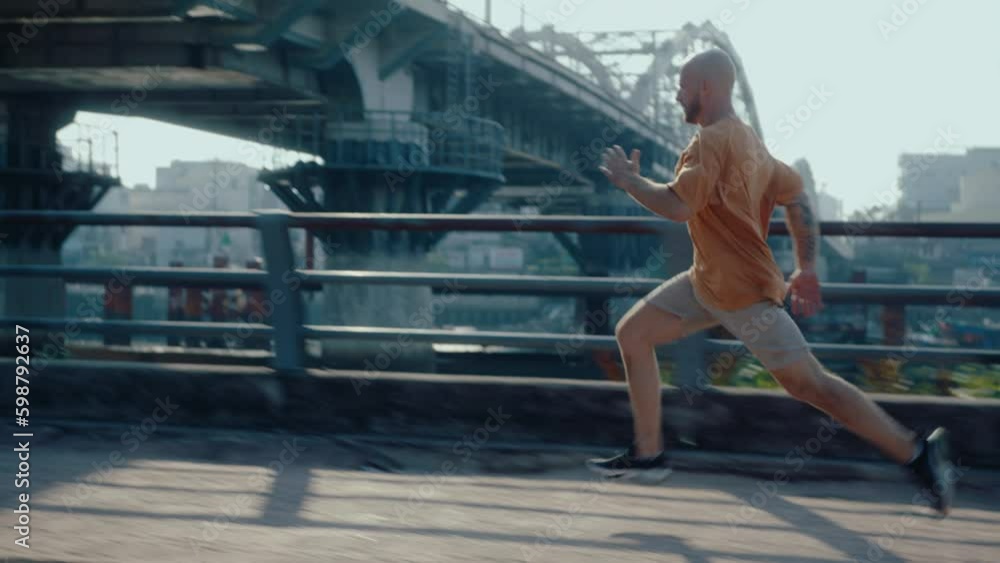 Young sportive man running fast along the street, training outdoors in the city on summer day. Zoom shot, shaky camera Young sportive man running fast along the street, training outdoors in the city on summer day. Zoom shot, shaky camera