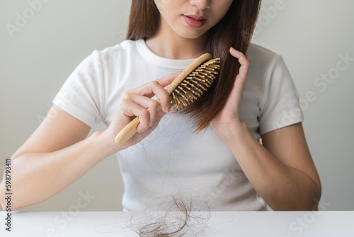 Damaged Hair, frustrated asian young woman, girl hand in holding brush splitting ends messy while combing hair, unbrushed dry long hair. Health care beauty, portrait isolated on white background. photo