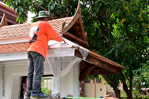 BANGKOK, THAILAND : MAY 05, 2023 - Workers are painting the Thai Wooden Roof of the pavilion in the Thai Temple at Thailand. photo