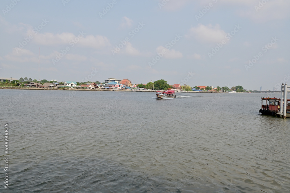 BANGKOK, THAILAND - May 11, 2023 : Wooden houses, Thai houses and buildings along the Chao Phraya River with white clouds and blue sky background, Town Bangkok Waterfront, Thailand.
