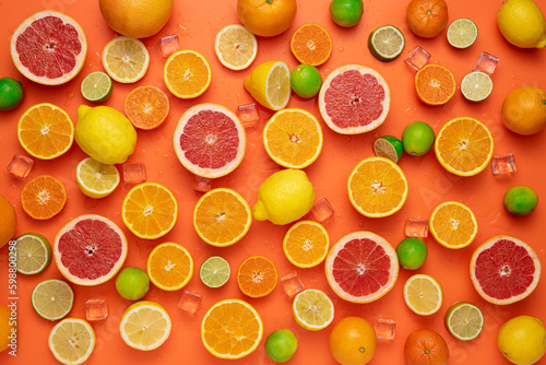Concept for fresh, fruity and juicy fruit. Top view. Delicious fruit background made of many different colorful fresh cut, halved and whole citrus fruits on an orange background