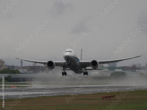 雨の日に水しぶきをあげながら離陸していく旅客機