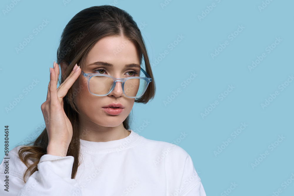 Young woman in stylish blue framed spectacles, isolated on blue background. Eyesight Vision Fashion. Young woman in stylish blue framed spectacles, isolated on blue background. Eyesight Vision Fashion.