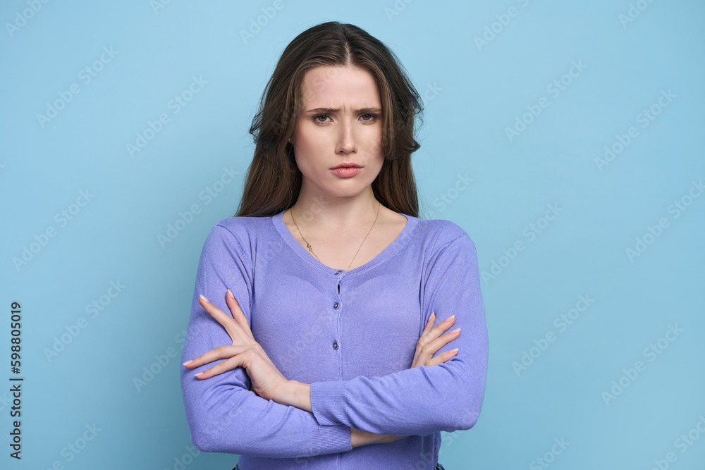 Isolated portrait on blue background of perplexed confuded woman with arms folded Isolated portrait on blue background of perplexed confuded woman with arms folded