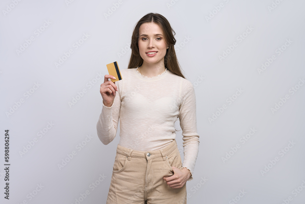 Beautiful confident Caucasian young woman in casual clothes, showing at camera a golden credit card Beautiful confident Caucasian young woman in casual clothes, showing at camera a golden credit card
