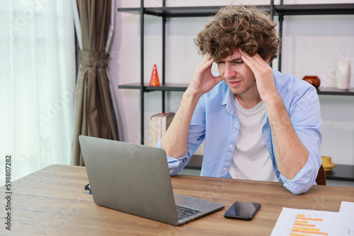 Young adult businesswoman touching his head on table in office after bad news business failure or get fired and feeling discouraged, distraught and hopeless in modern office.