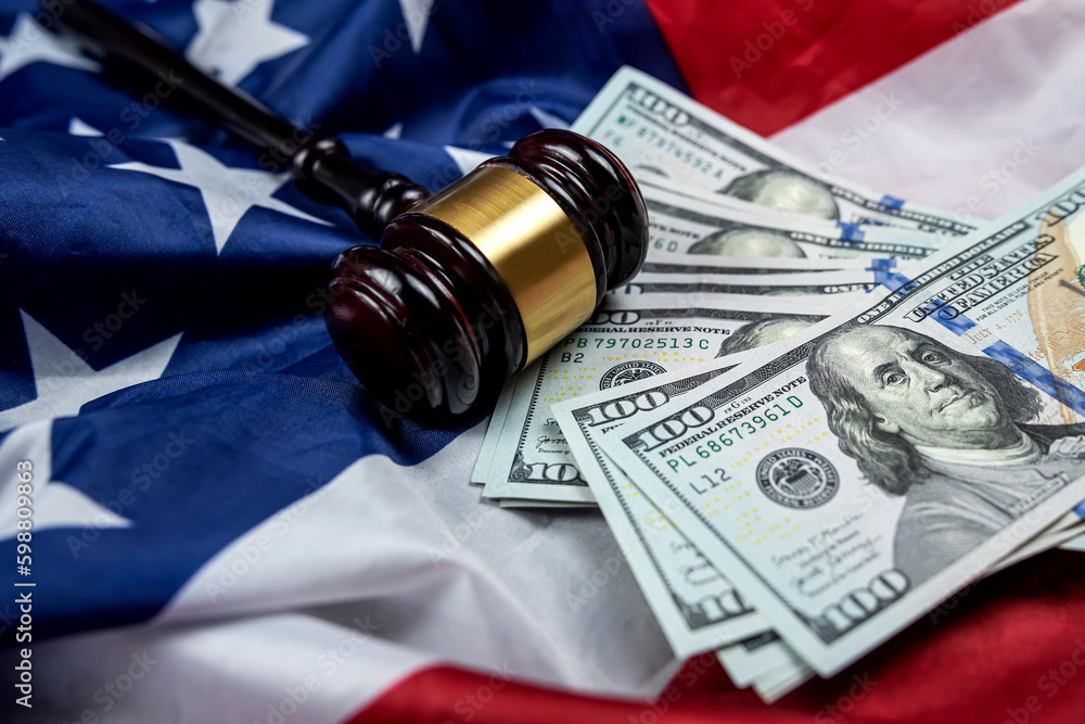 hundred dollar bills and a judge's gavel are placed on an American flag.