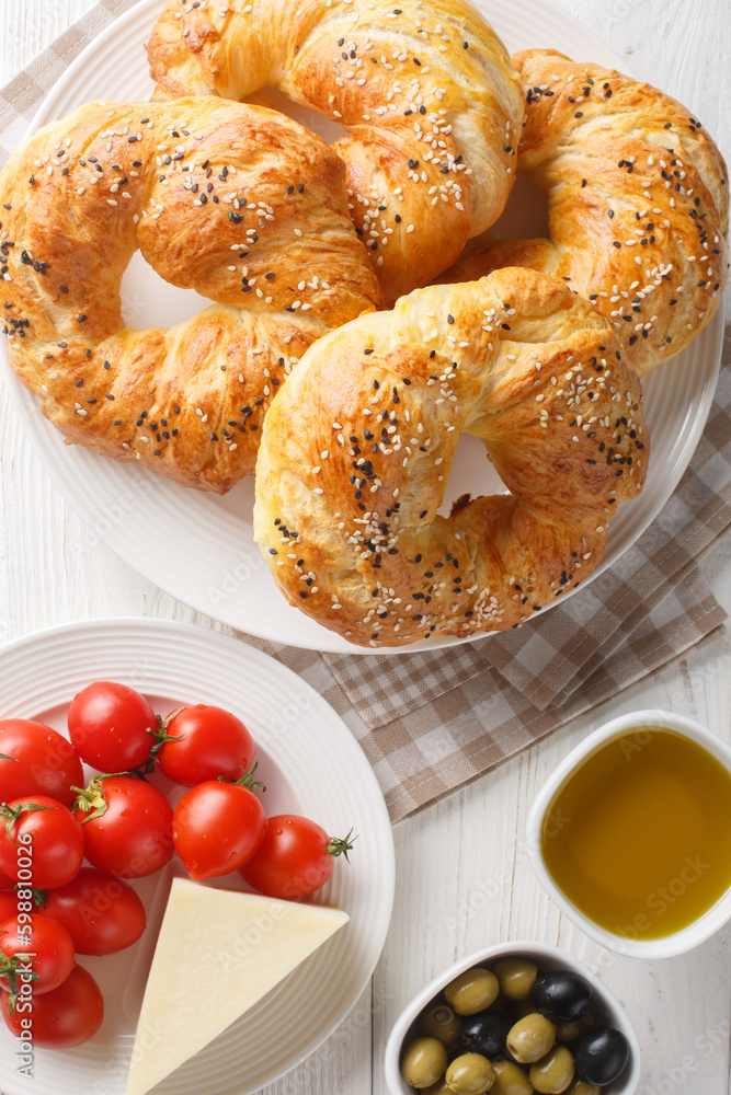 Acma Turkish Style Soft Bagels served with tomato, cheese, olive and olive oil closeup on the plate on the table. Vertical top view from above Acma Turkish Style Soft Bagels served with tomato, cheese, olive and olive oil closeup on the plate on the table. Vertical top view from above