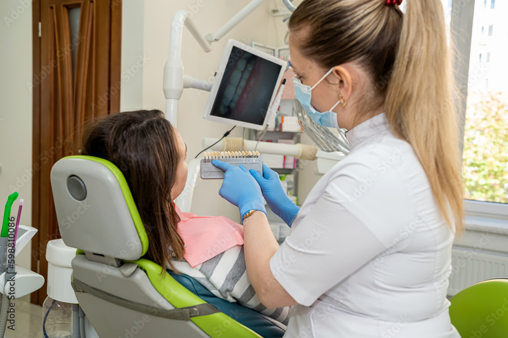 Dentist's hand holding tooth color and examining patient's teeth Dentist's hand holding tooth color and examining patient's teeth