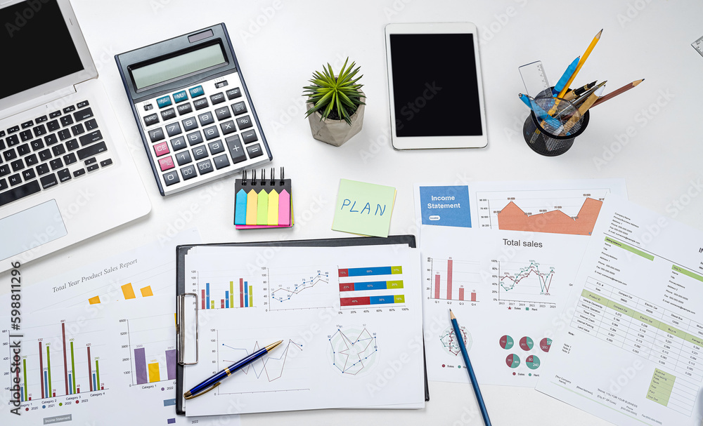 Business office desk with graph or annual report with laptop, pen calculator Business office desk with graph or annual report with laptop, pen calculator