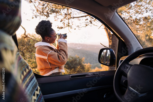 Wallpaper Mural young african woman taking photos of nature with a camera during a road trip in camper van, concept of van life and travel adventures Torontodigital.ca