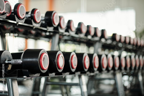 Rack with various dumbbells in gym, selective focus