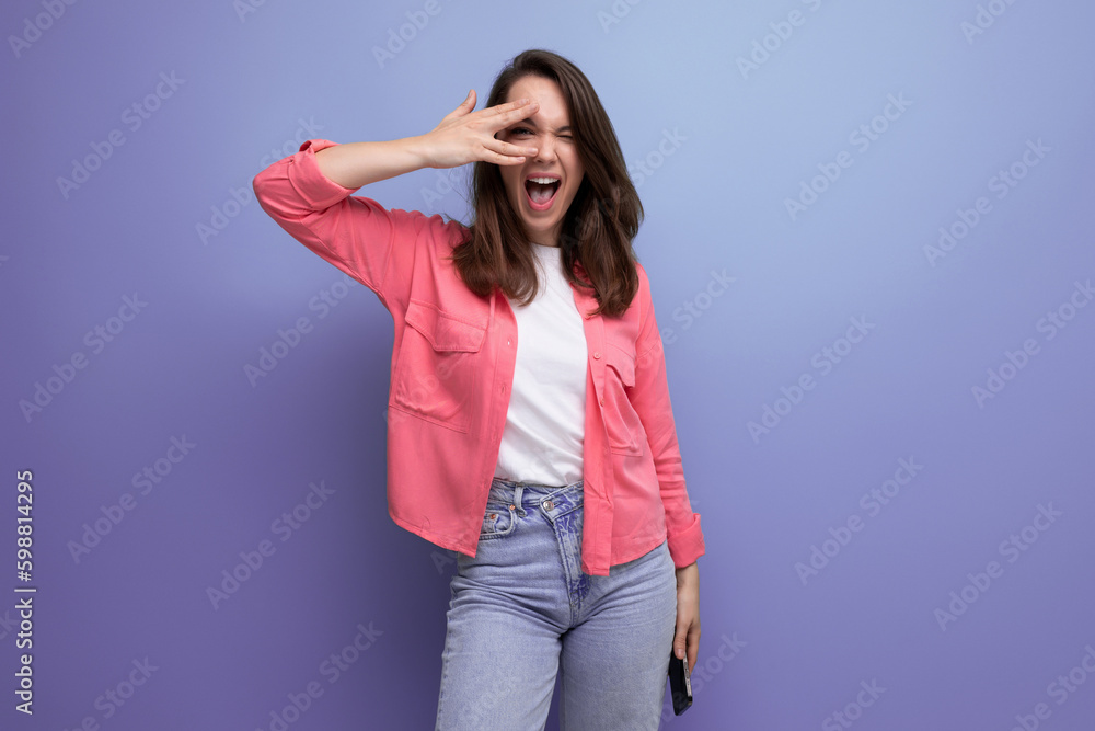 charming smiling brunette young woman in a pink shirt and jeans on a studio isolated background charming smiling brunette young woman in a pink shirt and jeans on a studio isolated background