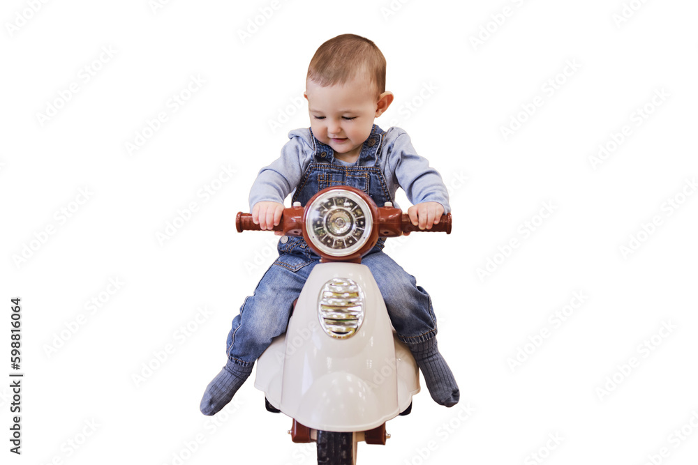 Happy baby boy rides a plastic children motorcycle in the playroom, isolated on a white background. A smiling child drives a moped toy, isolated on a white background. Kid age one year Happy baby boy rides a plastic children motorcycle in the playroom, isolated on a white background. A smiling child drives a moped toy, isolated on a white background. Kid age one year