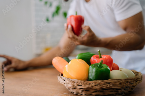 Male prepares cooking healthy food from fresh vegetables and fruits in kitchen room.