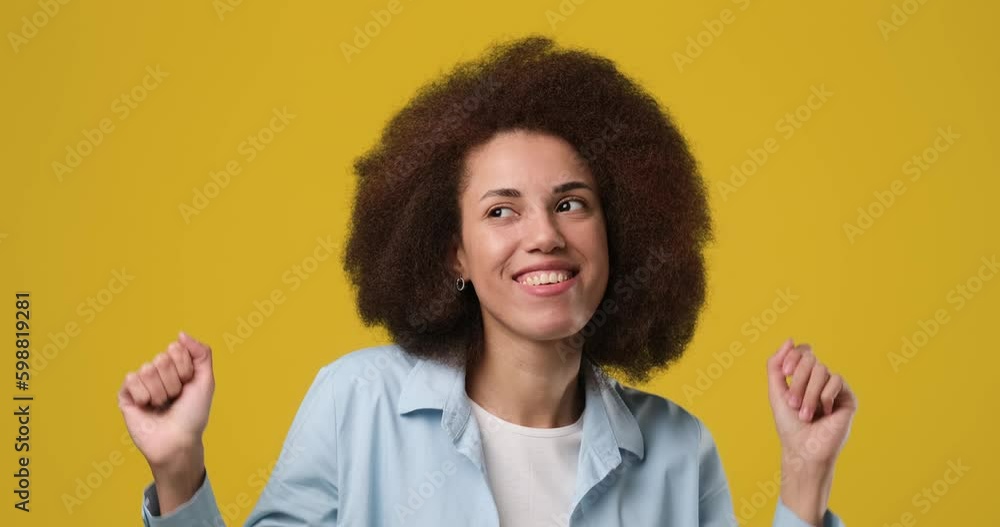 Young african american woman with afro hair having fun smiling and dancing in studio against orange background Young african american woman with afro hair having fun smiling and dancing in studio against orange background
