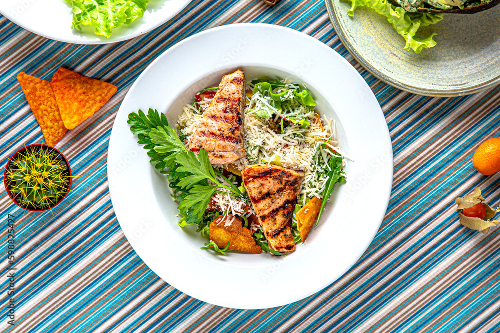 Traditional mexican food. Warm salad of grilled salmon, nachos, avocado and parmesan. Colorful Food Table Celebration Delicious Party Meal Concept. Traditional mexican food. Warm salad of grilled salmon, nachos, avocado and parmesan. Colorful Food Table Celebration Delicious Party Meal Concept.