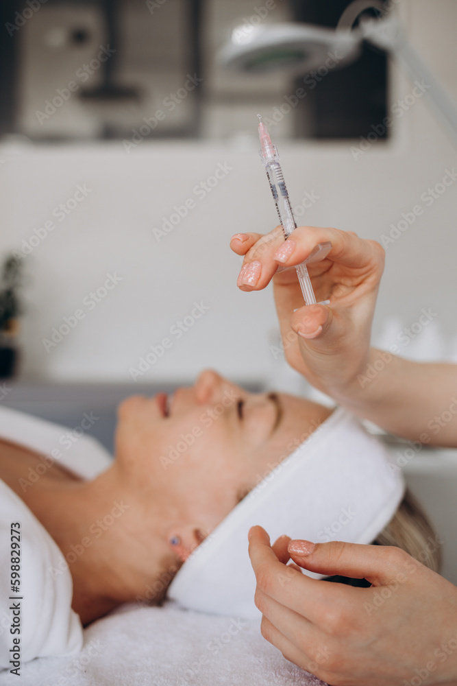 Beautician doctor with botulinum toxin syringe making injection to to remove crow's feet. Cheek volume enhance mesotherapy. Anti-aging treatment and face lift in cosmetology clinic Beautician doctor with botulinum toxin syringe making injection to to remove crow's feet. Cheek volume enhance mesotherapy. Anti-aging treatment and face lift in cosmetology clinic