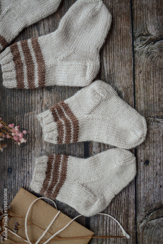 Brown baby socks made of soft cotton yarn, o dark wooden background