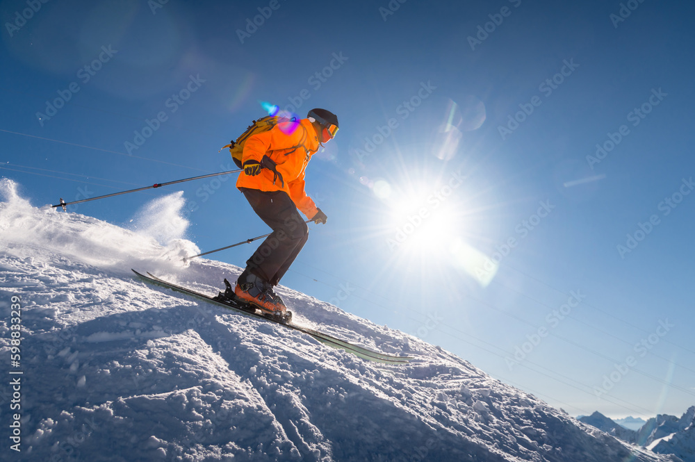 good skiing in snowy mountains. a nice winter day, an incredible ski drive from which a skier jumps against the backdrop of a snowy sunny day good skiing in snowy mountains. a nice winter day, an incredible ski drive from which a skier jumps against the backdrop of a snowy sunny day