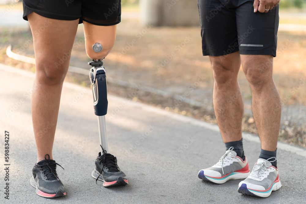 Low angle exercise walking woman with prosthetic leg and friend in the park Low angle exercise walking woman with prosthetic leg and friend in the park