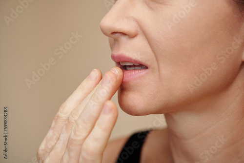 Mature woman applying nourishing balm on her dry lips
