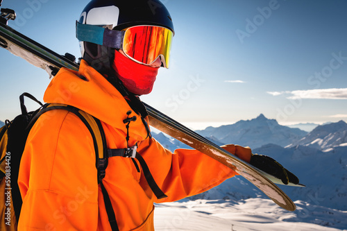 shot of a skier standing on top of a mountain with skis on his shoulder on a sunny winter day, sunlight, outdoor recreation, skiing, lifestyle, downhill sport concept © yanik88