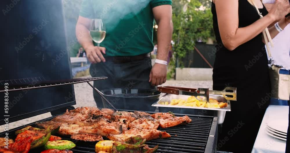 Picnic with friends. Summer barbecue with friends. Grilled pork, beef, lamb, chicken and vegetables. Close-up shot of opening the grill. BBQ meat grill for party