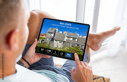 Foto Man looking at real estate website on tablet computer, searching for a new house