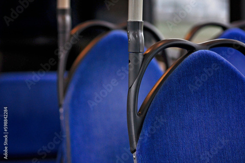 Bright blue seats in a bus with black and metallic details. Black handles on the blue seats in empty bus with no people. Going on a bus trip, Finnish public transport. © Maija