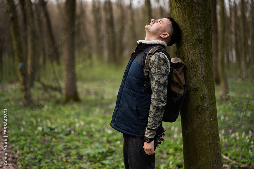 Portrait of man with backpack leaned his back against a tree on forest. Love to nature. Portrait of man with backpack leaned his back against a tree on forest. Love to nature.