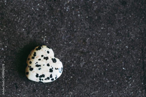 Pierre polie jaspe dalmatien en forme de coeur sur un fond noir