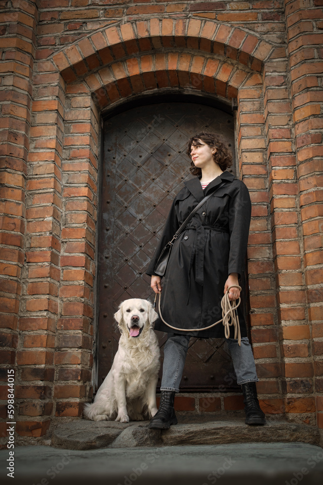 Beautiful girl with her golden dog near the door