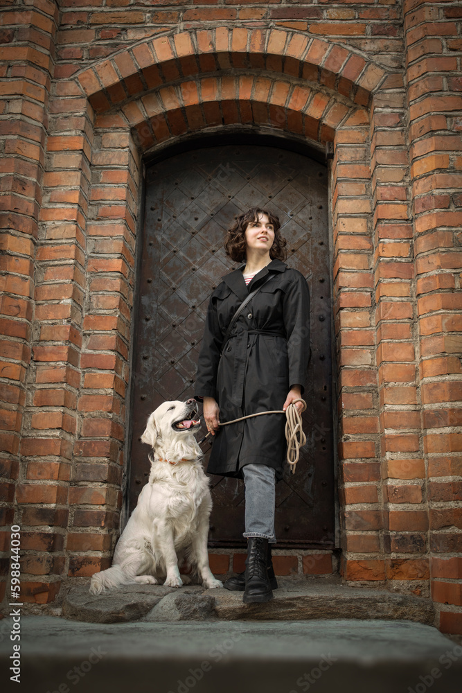 Beautiful girl with her golden dog near the door