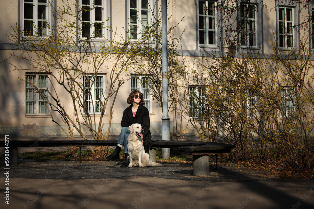 Cute funny girl portrait with her golden dog on street